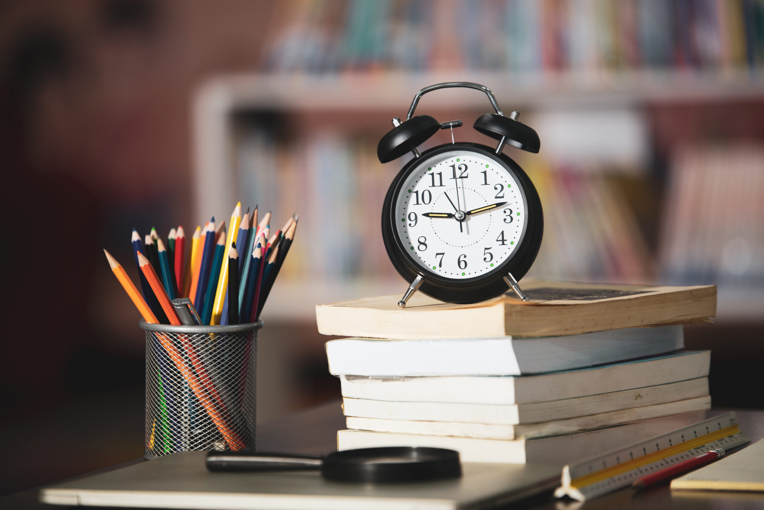 Book,laptop,pencil,clock on wooden table in library,education le